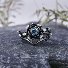 a black and white ring sitting on top of a gray rock next to some plants