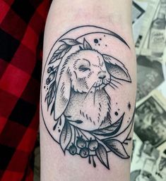 a black and white tattoo of a rabbit on the right arm with an olive branch around it