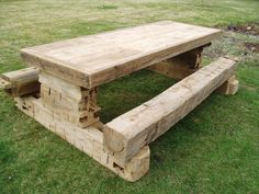 a wooden picnic table and bench made out of wood planks in the grass outside