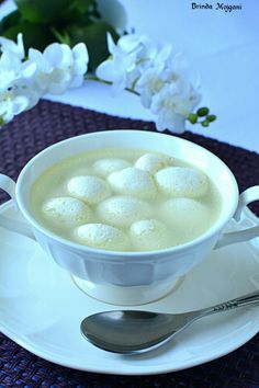 a cup of coffee with marshmallows in it on a saucer next to flowers