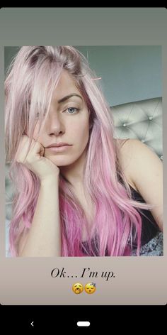 a woman with pink hair and blue eyes is looking at the camera while she has her hand on her chin