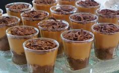 there are many desserts in small cups on the glass tray, ready to be eaten