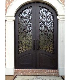 the front door to a house with an ornate iron design on it and a rug in front