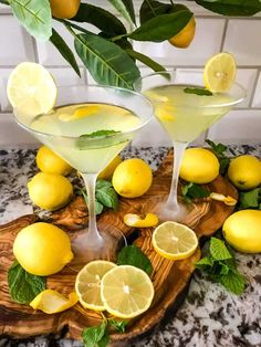 two martini glasses with lemons and mint on a cutting board