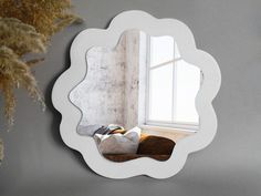 a mirror that is on the wall next to a plant and some pillows in front of it