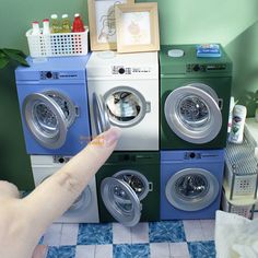 a hand pointing at four washers stacked on top of each other in a room