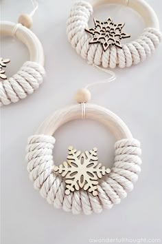 two white bracelets with snowflake pendants on them, one is made out of rope and the other has a wooden bead