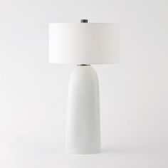 a white table lamp with a white shade on it