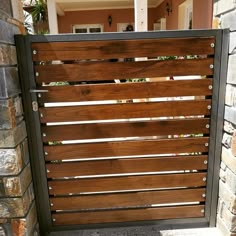 a wooden gate with metal bars on the top and bottom, in front of a brick wall