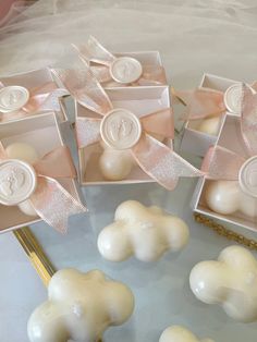 some white soaps with pink bows are on a table next to other small ones