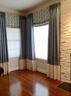 a living room with hard wood floors and two windows covered in blue drapes, along with a fireplace