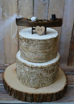 a rustic wedding cake with a wooden slice as the topper and initials on it