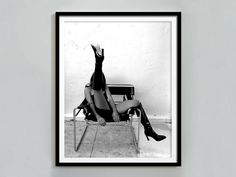 a black and white photo of a woman sitting in a chair with her legs up