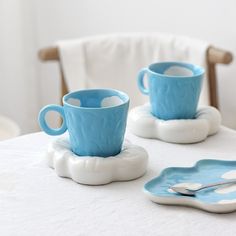 two blue cups and saucers on a white table