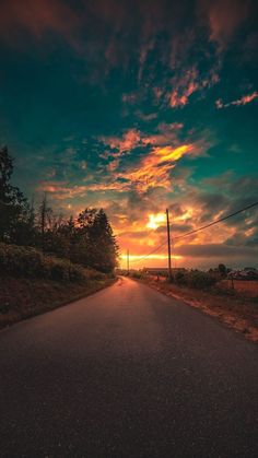 the sun is setting over an empty road