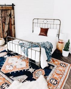 a bedroom with a metal bed frame and rugs on the floor next to it