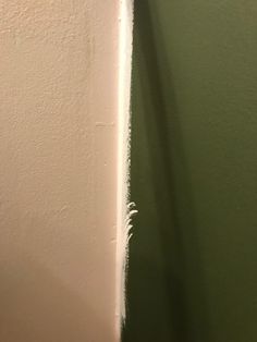 the corner of a room with green paint on it and a white wall in the background