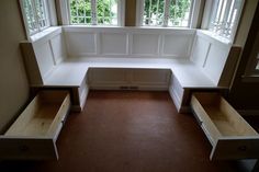 an empty room with three windows and two benches in front of the window seat area