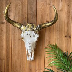 an animal skull with gold and white decorations on it's head against a wooden wall