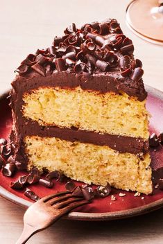 a piece of cake with chocolate frosting on a red plate next to a fork