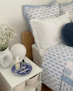 a bed with blue and white decor on top of it next to a night stand