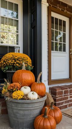 some pumpkins and gourds are sitting in a bucket on the front porch