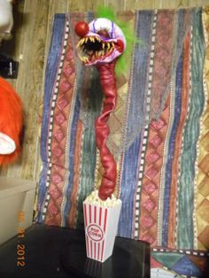 a creepy clown head sitting on top of a table next to a movie theater curtain