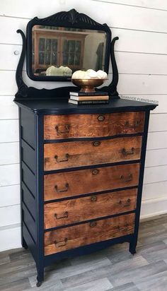 an old dresser has been painted black and is next to a mirror on the wall