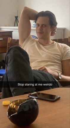 a man sitting on top of a wooden table next to a computer mouse and cell phone