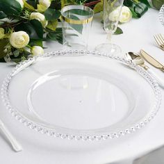 the table is set with white roses and gold cutlery, along with silverware