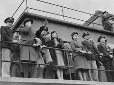 a group of people standing on top of a boat next to each other in uniform