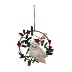 an owl ornament hanging from a twig on a branch with red berries