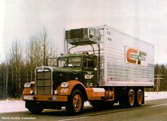 a semi truck driving down the road in the wintertime with snow on the ground and trees behind it