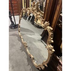 an ornate gold framed mirror on display in a room with other antique furniture and mirrors