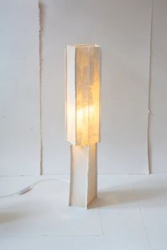 a light that is on top of a white floor lamp with a cord attached to it