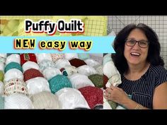 a woman standing in front of a pile of quilts