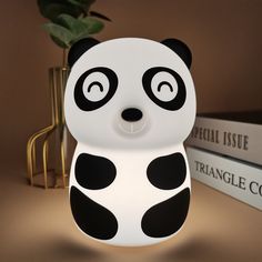 a panda bear lamp sitting on top of a table next to books and a plant