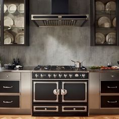 a stove top oven sitting inside of a kitchen next to a wall with plates on it