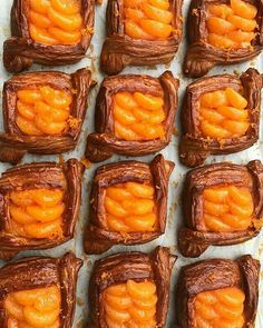 there are many pieces of chocolate with oranges in them on the baking sheet, ready to go into the oven