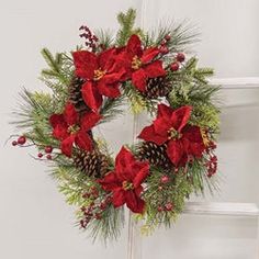 a christmas wreath with red poinsettis and pine cones on a door handle