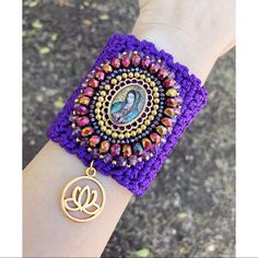 a woman's arm with a purple bracelet that has a buddha image on it