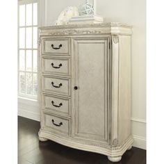 an antique white armoire with drawers and knobs