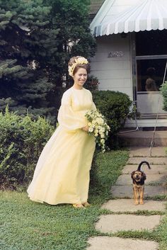 an old photo of a woman in a yellow dress with a dog on a leash