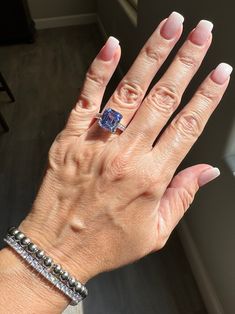 a woman's hand with white nails and a blue ring on her left wrist