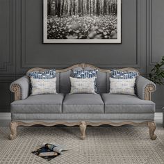 a grey couch with blue and white pillows in a room next to a painting on the wall