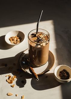 a glass filled with liquid sitting on top of a table next to bowls and spoons