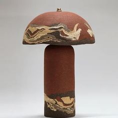 a mushroom shaped object with brown and gold paint on it's top, sitting in front of a gray background