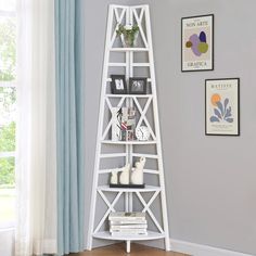 a white shelf with books on it in front of a gray wall and blue curtains