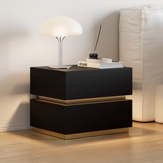 a nightstand with a lamp on top of it next to a white bed and pillows