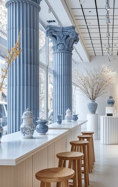 a row of blue and white vases sitting on top of a counter next to tall windows